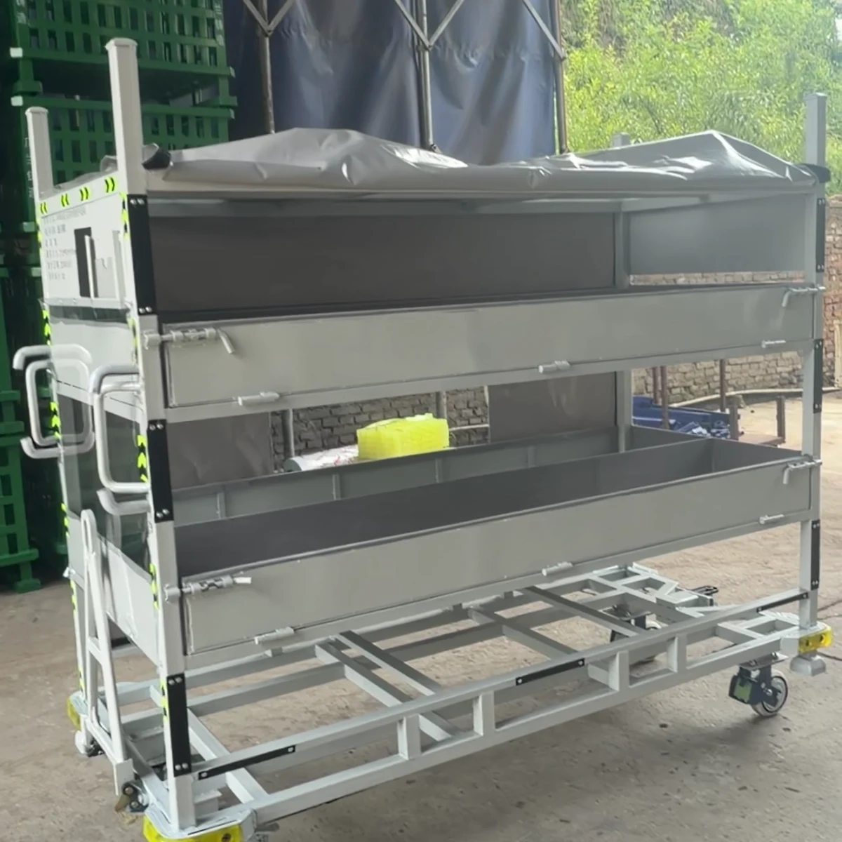 Real product photo of a covered returnable parts trolley with enclosure cover, access panel and wheeled returnable frame — configuration view 4