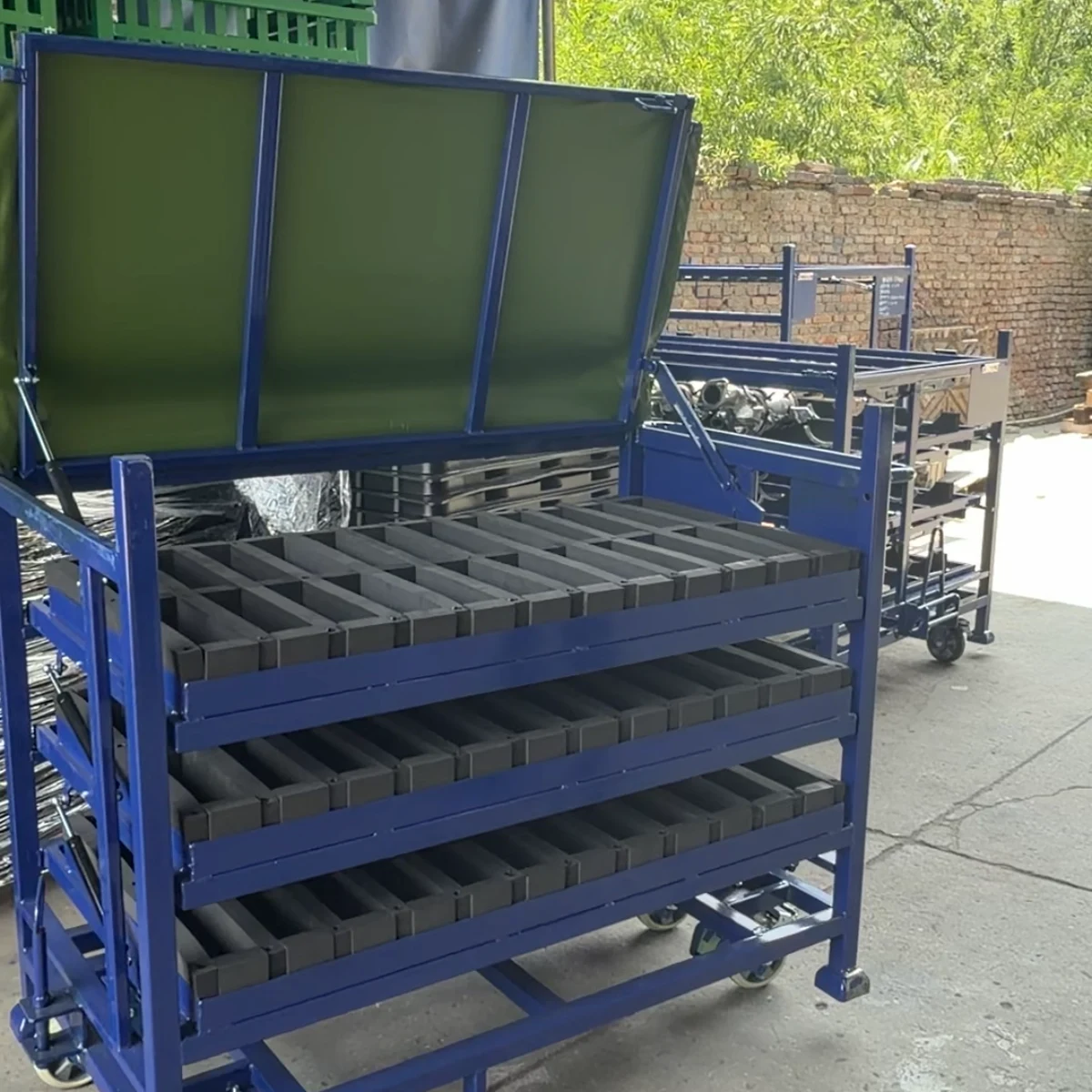 Real product photo of a gas strut tilting tray rack with gas-strut-assisted tilting trays and foam locators