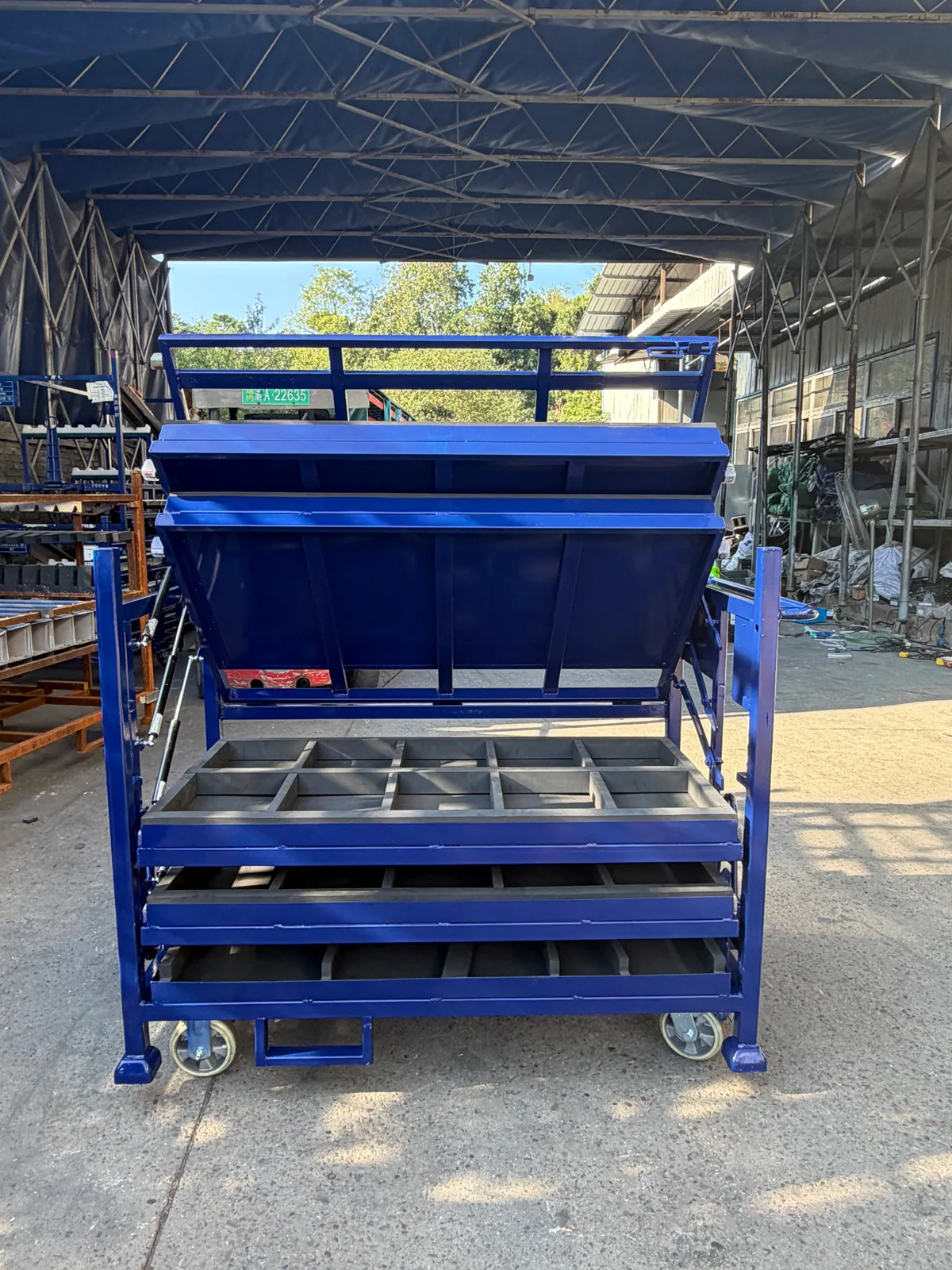 Blue automotive returnable rack with open gas-strut-assisted tilting tray and grey divided channels